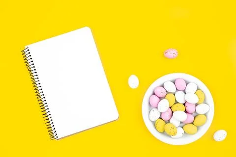 Colored Easter eggs and a blank notepad on a yellow background. Stock Photos