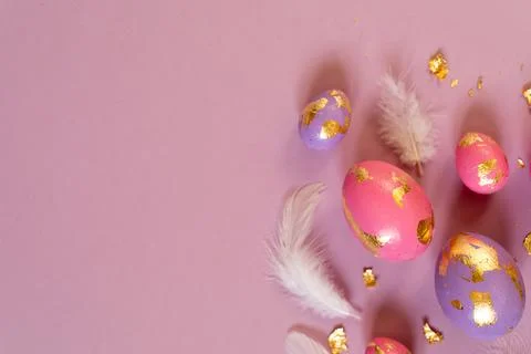 Colored Easter eggs and feathers on the violet background, copy space. Stock Photos
