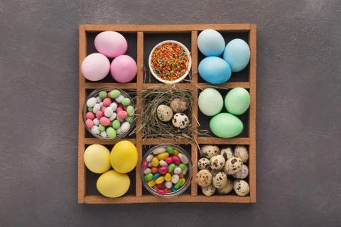 Colored easter eggs and small candies in frame on gray background Foto stock