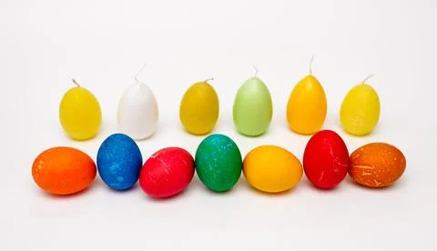 Colored easter eggs arranged in a row against a background of candles Stock Photos