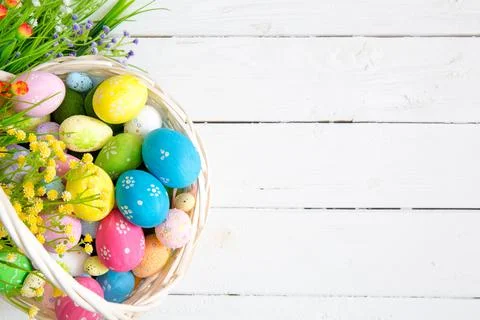 Colored easter eggs in the basket and spring flowers on wooden background Stock-Fotos