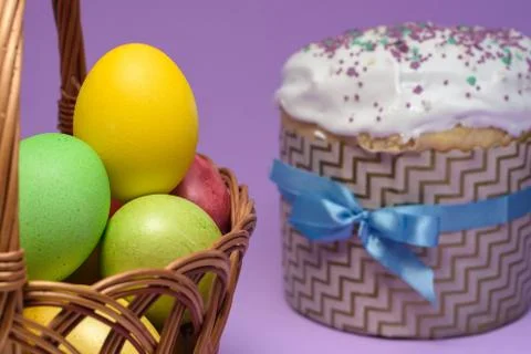 Colored Easter eggs in a basket, Easter cake on the right in the background Stock Photos