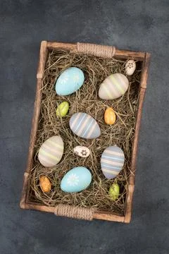 Colored easter eggs in a basket with hay, empty copy space for text Stock Photos
