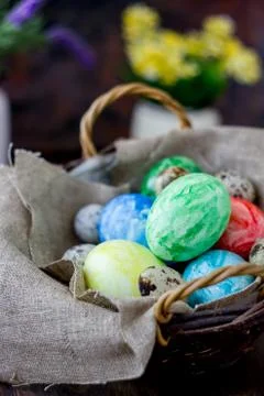 Colored easter eggs on basket over rustic table. Stock Photos