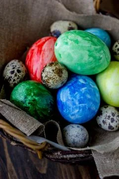 Colored easter eggs on basket over rustic table. Stock Photos