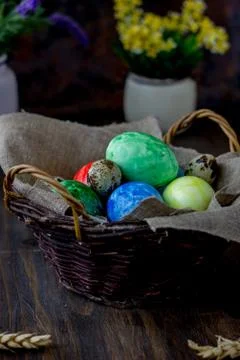 Colored easter eggs on basket over rustic table. Stock Photos