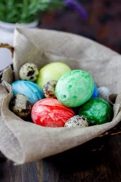 Colored easter eggs on basket over rustic table. Stock Photos