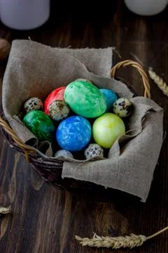 Colored easter eggs on basket over rustic table. Stock Photos