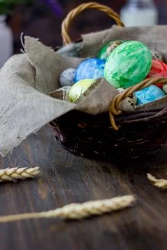 Colored easter eggs on basket over rustic table. Fotos Stock