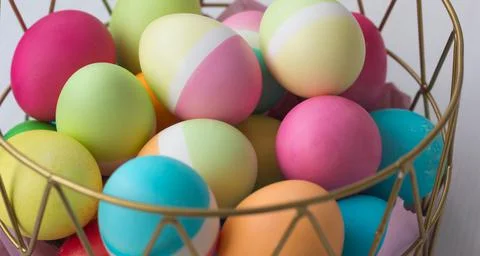 Colored Easter eggs in a basket on the table Stock Photos