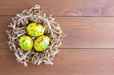 Colored Easter eggs in brown paper shavings. On a wooden background. 库存照片