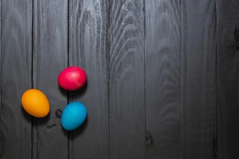 Colored Easter eggs on dark wooden boards top view. copyspace Stock Photos