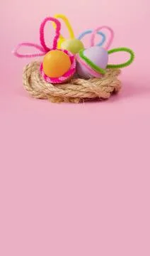 Colored Easter eggs with decorated bunny ears lie in a wicker basket Stock Photos