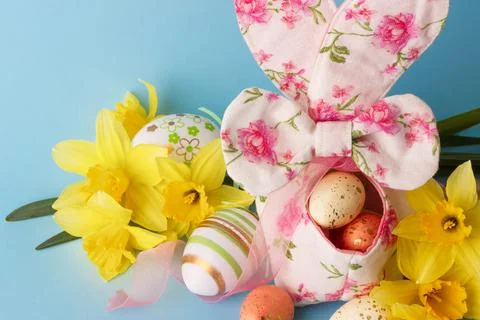 Colored Easter eggs in decorative basket and a bouquet of yellow narcissus Stock Photos