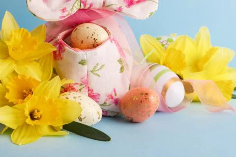 Colored Easter eggs in decorative basket and a bouquet of yellow narcissus Stockfoto's