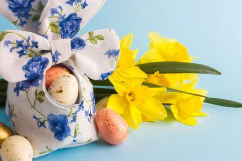 Colored Easter eggs in decorative basket and a bouquet of yellow narcissus Stock Photos