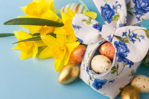 Colored Easter eggs in decorative basket and a bouquet of yellow narcissus 写真素材