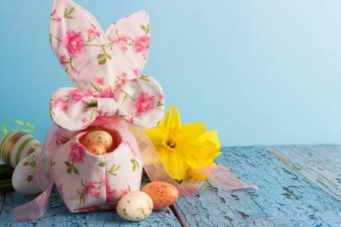 Colored Easter eggs in decorative basket and a bouquet of yellow narcissus 库存照片