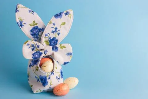 Colored Easter eggs in decorative basket, blue background 库存照片
