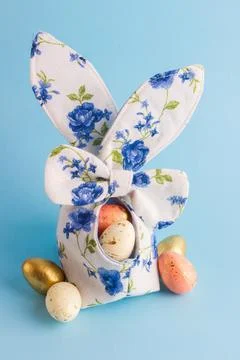 Colored Easter eggs in decorative basket, blue background Fotos Stock