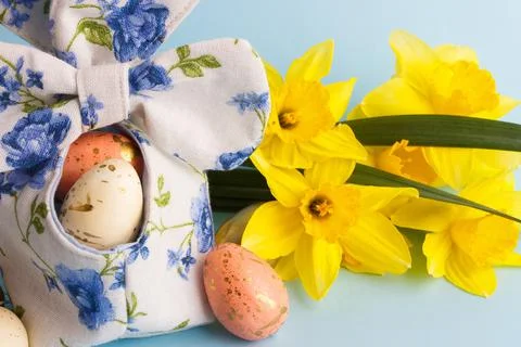 Colored Easter eggs in decorative basket and a bouquet of yellow narcissus Stock-Fotos