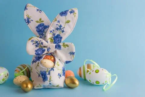 Colored Easter eggs in decorative basket, blue background Stock-Fotos