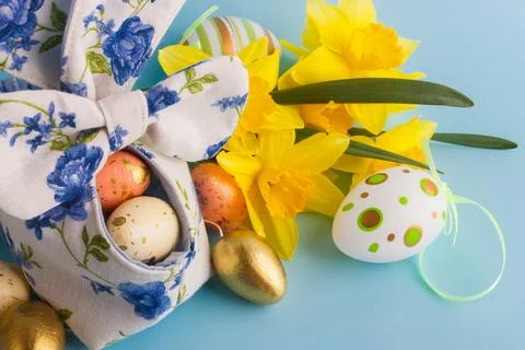 Colored Easter eggs in decorative basket and a bouquet of yellow narcissus Stock Photos