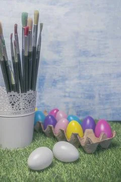 Colored Easter eggs in egg on grass with paint brushes Stock Photos