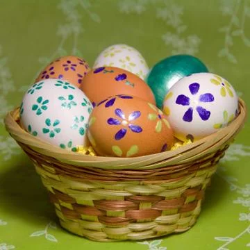 Colored  easter eggs  with flower  laying in wood basket Stock Photos