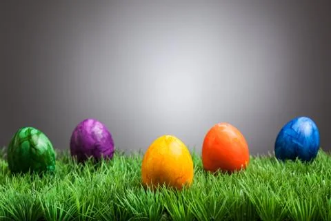 Colored easter eggs in grass, gray background 스톡 사진