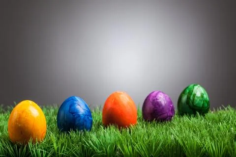 Colored easter eggs in grass, gray background Stock Photos