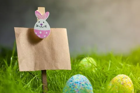 Colored Easter eggs in the grass next to Kraft paper topper decorated with an Stock Photos