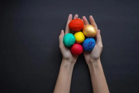 Colored easter eggs in hands on a black background Stock Photos
