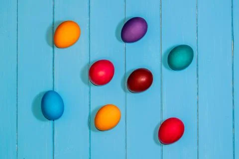 Colored Easter eggs on light blue wooden boards top view. red, blue, orange,  Stock Photos