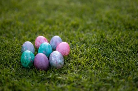 Colored easter eggs lying in a row on the grass Stock Photos