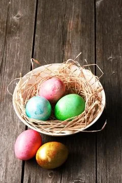 Colored easter eggs in nest on wooden table Stock Photos