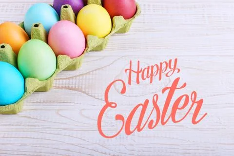 Colored Easter eggs in a pan, on a white wooden table. Text, happy easter. Stock Photos