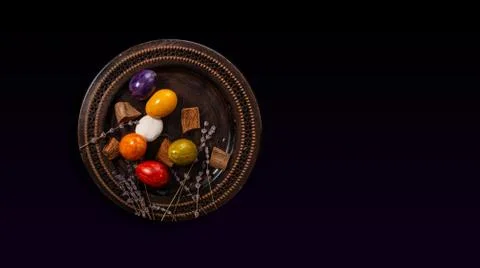 Colored easter Eggs in a plate with black background and copy space. With gra Stock Photos