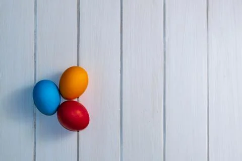 Colored Easter eggs on white wooden boards top view. red, blue, orange, holid Stock Photos