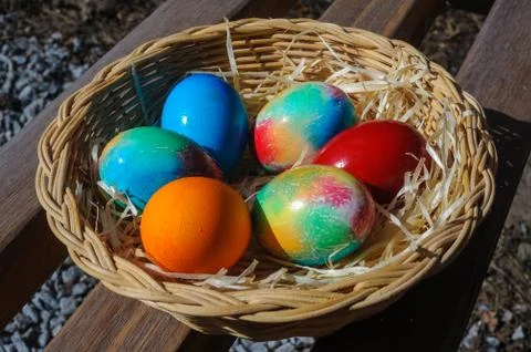 Colored Easter eggs in a wicker basket Stock Photos