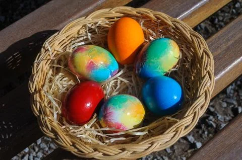 Colored Easter eggs in a wicker basket Stock Photos