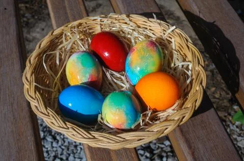 Colored Easter eggs in a wicker basket Stock Photos