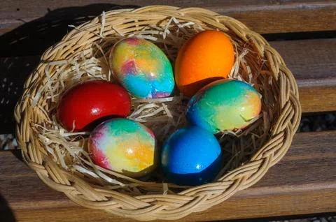 Colored Easter eggs in a wicker basket Stock Photos