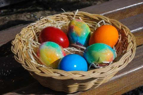 Colored Easter eggs in a wicker basket Stock Photos