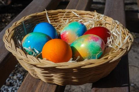 Colored Easter eggs in a wicker basket Stock Photos