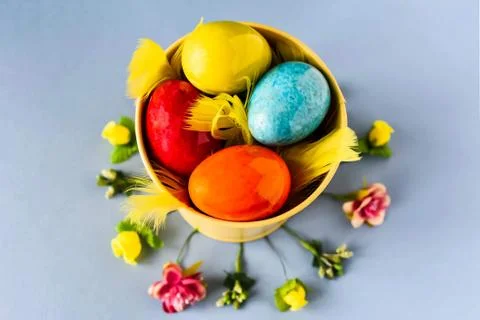 Colored easter eggs in a yellow bucket on a blue background Stock Photos