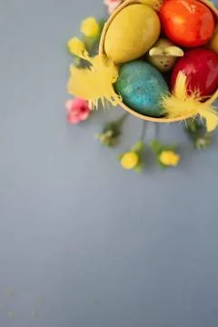 Colored easter eggs in a yellow bucket on a blue background Stock Photos