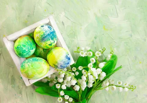 Colored eggs in box with lilies of the valley Foto stock