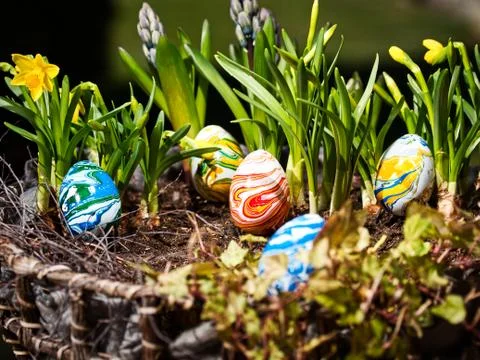 Colored eggs in a easter basket iwith flowers Stock Photos