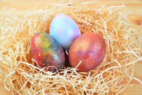 Colored eggs in a nest of straw Stock Photos